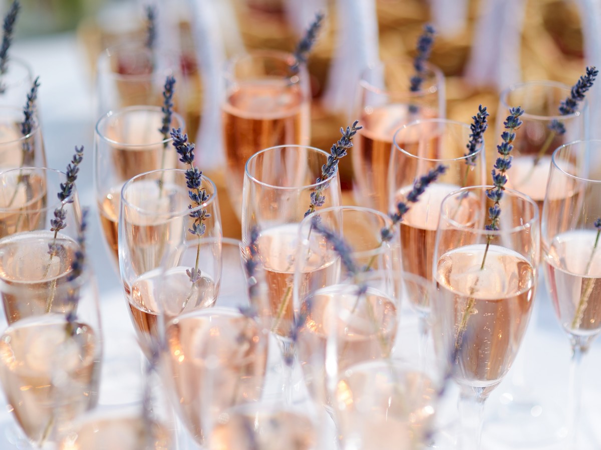 Glasses filled with rosé wine, garnished with sprigs of lavender, arranged on a table, creating an elegant and festive presentation.