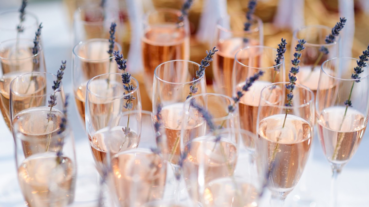 Glasses filled with rosé wine, garnished with sprigs of lavender, arranged on a table, creating an elegant and festive presentation.